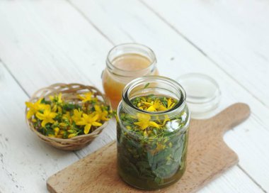 Hiperikum perforatum tentürü, yaygın olarak St John 's wort olarak bilinir. İçinde ve kesme tahtasının üzerinde taze sarı St John otu çiçekleri olan tentür. Geleneksel bitkisel ilaçlar.