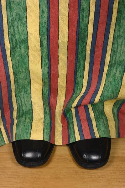 Nero Scarpe Vestito Sbirciando Dietro Tende Colorate Sul Pavimento Legno Foto Stock