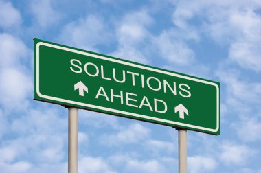Solutions ahead concept green destination signboard road sign, white text frame and arrows, grey pole posts, large detailed horizontal signpost perspective closeup, sunny summer sky cloudscape and clouds background motivational roadside signage