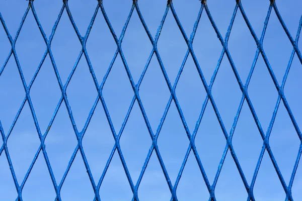 青い空に対する青いダイヤモンド型のフェンスの詳細 — ストック写真