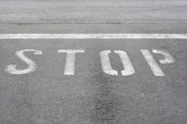 Detail of an asphalt road with white painted letters STOP