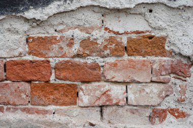 Altında çatlak faşit ve tuğlalar olan eski bir duvarın ayrıntıları