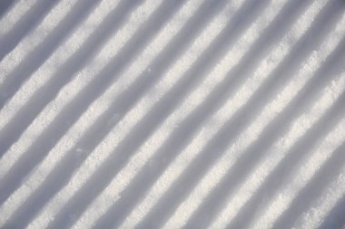 Karda ratrak izleri olan bir kayak yamacının ayrıntıları