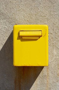 Duvarın dış kısmında metal sarı bir posta kutusu var.