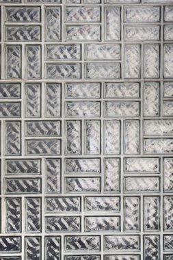 Dikdörtgen şeklindeki cam bloklardan yapılmış desenli bir duvar, ızgara benzeri bir şablon oluşturuyor. 