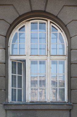 Beyaz ahşap çerçeveli eski, kavisli bir pencere, biraz aralık, caddenin karşısındaki binayı yansıtıyor.