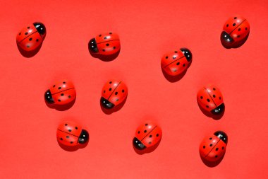 Kırmızı kağıt üzerinde küçük tahta uğur böceği heykelcikleri