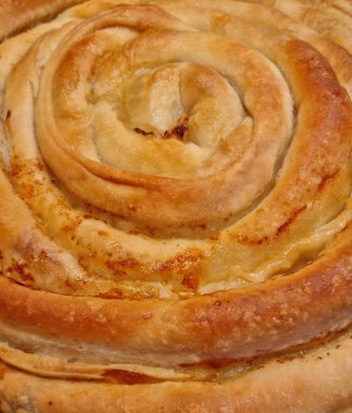 Taze pişmiş, altın-kahverengi, spiral şekilli burek detayı.