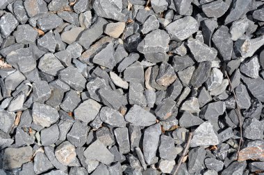 Çeşitli boyutlarda düzensiz, gri taş parçaları yoğun bir şekilde bir araya toplanmış.