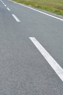 Trafik şeritlerini işaretleyen beyaz çizgili asfalt bir yol.