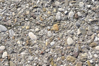 Gömülü çakıl ve çeşitli büyüklükteki taşlar ile beton yüzeyin yakın görüntüsü