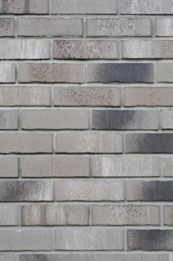 Koyu yamalı gri dekoratif tuğlalardan oluşan bir duvar, desenli bir yüzey oluşturuyor.