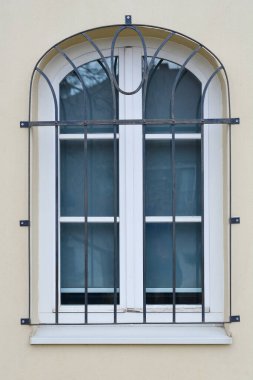 Sarı duvarında siyah metal ızgara olan kemerli bir pencere.