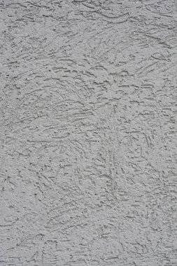 Sert, desenli yüzeyi olan gri bir çimento cephesinin yakın çekimi.