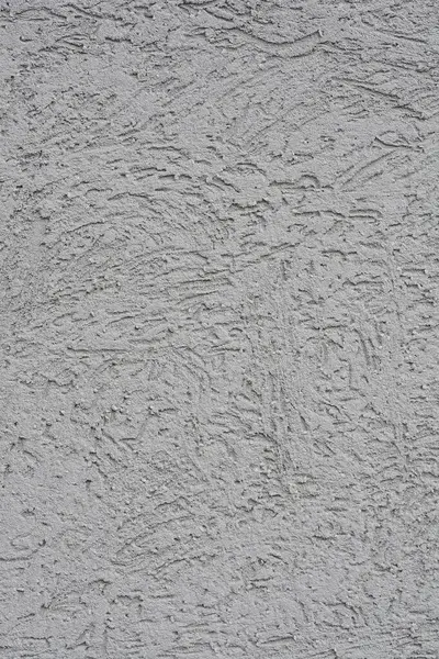 Sert, desenli yüzeyi olan gri bir çimento cephesinin yakın çekimi.