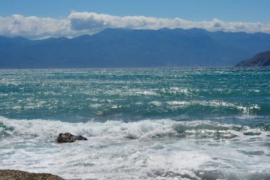 Krk Adası 'ndaki Baska sahilinden Adriyatik Denizi manzarası. Sahile vuran dalgaların arka planda Velebit sıradağları var.