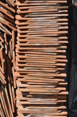 Yıpranmış dokularını ve toprak tonlarını gösteren düzgünce düzenlenmiş eski çatı kiremitleri.