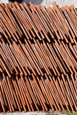 Yıpranmış dokularını ve toprak tonlarını gösteren düzgünce düzenlenmiş eski çatı kiremitleri.