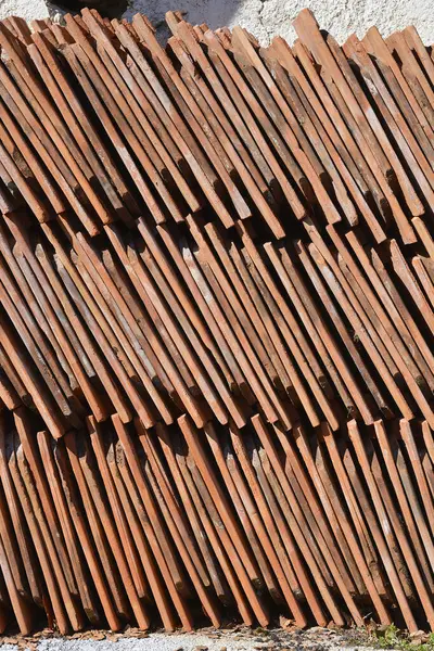 Yıpranmış dokularını ve toprak tonlarını gösteren düzgünce düzenlenmiş eski çatı kiremitleri.