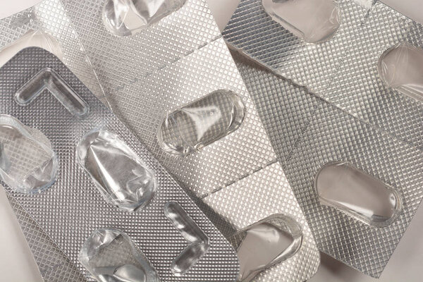 Крупный план использованных пузырьков упаковки таблеток, подчеркивая пустые отсеки и металлическую текстуру упаковки
