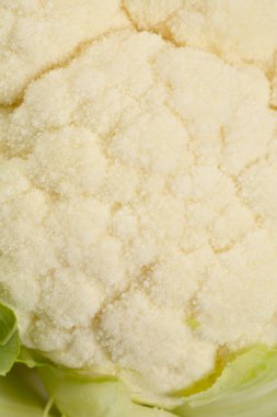 Beyaz çiçeklerini ve çevresini çevreleyen yeşil yaprakları vurgulayan taze karnabahar kafasının yakın çekimi.