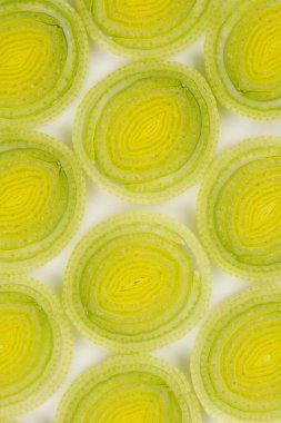 Dilimlenmiş pırasa mermilerinin yukarıdan aşağıya yakın görüntüsü, eşmerkezli dairelerini ve şeffaf dokusunu gösteriyor.