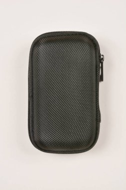 Tarafsız bir arkaplanda küçük, siyah, dikdörtgen, fermuarlı bir dosyanın yukarıdan aşağıya çekilmiş bir fotoğrafı.