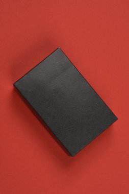 Tepeden tırnağa küçük, dikdörtgen, siyah desenli, kırmızı arka planda bir kutu.