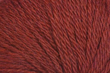 Koyu kırmızı ipliğin yakın plan görüntüsü, dokusunu vurguluyor ve sıkıca sarmalanıyor.