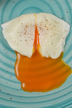 Açık mavi benekli bir tabakta servis edilen, pişmiş yumurta ve cıvık sarısı.