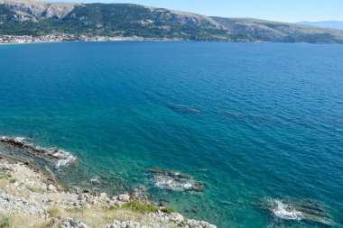 Baska Körfezi 'nin batısındaki kayalık arazide sarp kayalıklar mavi denize doğru inerken Baska köyü uzaktan görülebiliyor.