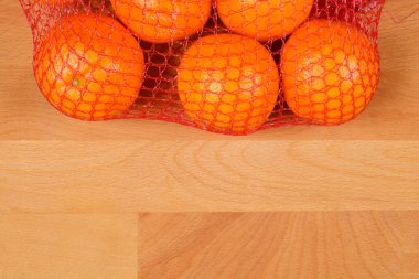 Kırmızı bir çantadaki birkaç portakalın yakın plan fotoğrafı, canlı renklerini ve dokulu derilerini gösteriyor.