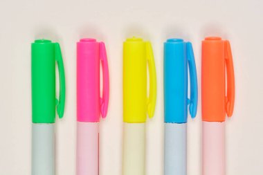 Yakın plan, ön plan beş renkli keçeli kalem, açık arkaplan üzerine dizilmiş.