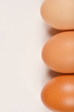 Arka arkaya üç kahverengi yumurtanın yakın plan, dikey çekimi, her biri eşsiz dokular ve ince renk farklılıkları ile.