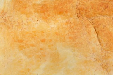 Fırında pişmiş bir böreğin dokulu yüzeyinin, altın rengini ve ayrıntılı desenini gösteren yakın plan bir fotoğrafı.