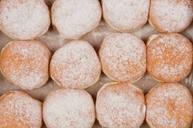 Hafif bir yüzey üzerine sıralanmış taze pişmiş çöreklerin toz şekerle serpilmiş ayrıntılı bir genel çekimi.