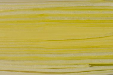 Açık arkaplanda üst üste yığılmış ince, yatay yeşil pırasa katmanlarının aşırı yakın plan çekimi.