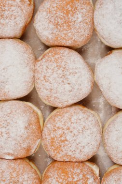 Hafif bir yüzey üzerine sıralanmış taze pişmiş çöreklerin toz şekerle serpilmiş ayrıntılı bir genel çekimi.