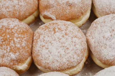 Hafif bir yüzey üzerine sıralanmış taze pişmiş çöreklerin toz şekerle serpilmiş ayrıntılı bir genel çekimi.