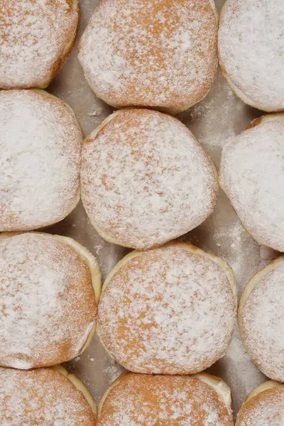 Hafif bir yüzey üzerine sıralanmış taze pişmiş çöreklerin toz şekerle serpilmiş ayrıntılı bir genel çekimi.
