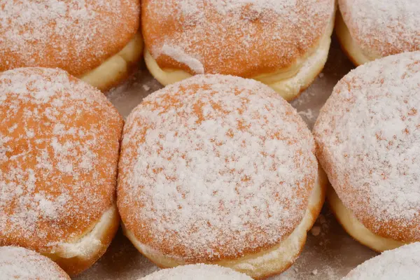 Hafif bir yüzey üzerine sıralanmış taze pişmiş çöreklerin toz şekerle serpilmiş ayrıntılı bir genel çekimi.
