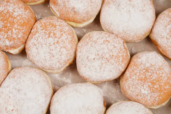 Hafif bir yüzey üzerine sıralanmış taze pişmiş çöreklerin toz şekerle serpilmiş ayrıntılı bir genel çekimi.