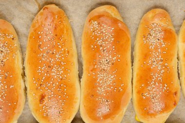 Parşömen kağıdına düzgünce yerleştirilmiş susam tohumları serpiştirilmiş taze ekmeklerin genel görünümü