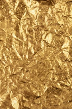 Yansıtıcı yüzeyini ve karmaşık kıvrımlarını gösteren buruşmuş altın folyonun yakın çekim dokusu.