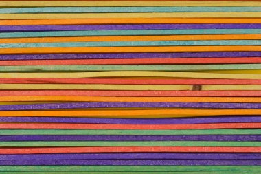 Yakından, yukarıdan aşağıya renkli el sanatları çubuklarının düzgün, paralel sıralarda dizilmiş, canlı bir doku ve desen gösteren bir görüntüsü.