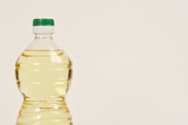 A close-up shot of a clear plastic bottle filled with yellow cooking oil against a light background