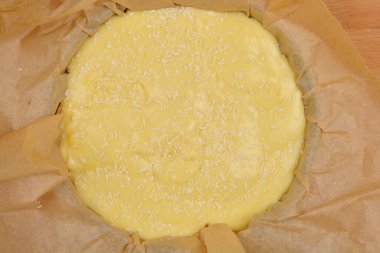 Açık sarı vanilya ve hindistan cevizi kremalı pasta seti mavi bir fırın kabında parşömen kağıdıyla kaplanmış.