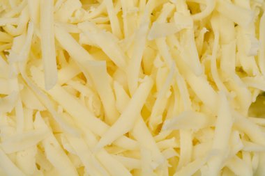 Parçalanmış peynirin yakın plan çekimi, deseni ve soluk sarı rengi sergileniyor.