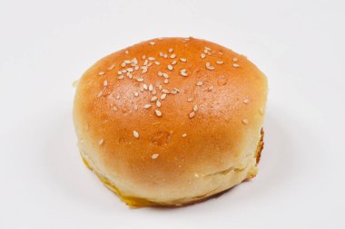 Arkaplanda susam tohumları serpiştirilmiş tek bir ev yapımı hamburger çöreği var.