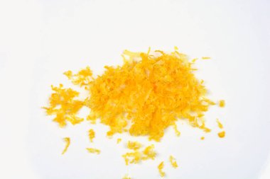 Beyaz bir yüzeye rendelenmiş küçük bir limon yığını konur, parlak sarı rengini ve ince dokusunu ön plana çıkarır.